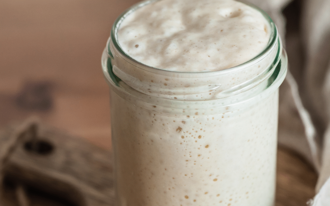 How to make a sourdough starter from scratch in a glass jar with bubbles showing fermentation