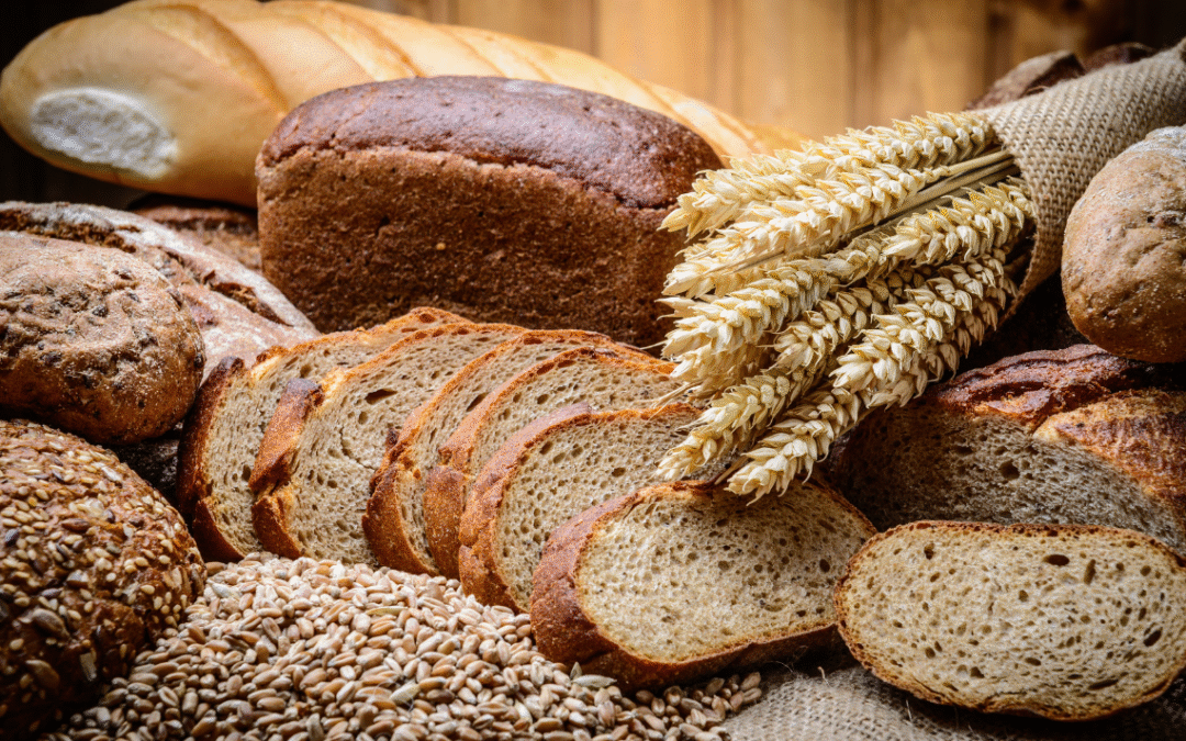 Assorted sourdough breads and sliced loaves displayed with wheat grains, highlighting natural fermentation and artisan baking.