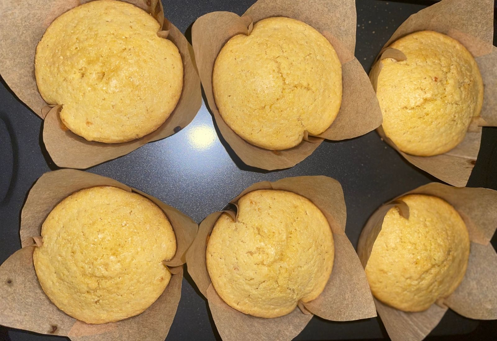 Half Dozen jumbo honey sourdough corn muffins baked in tulip liners with evenly domed golden tops.