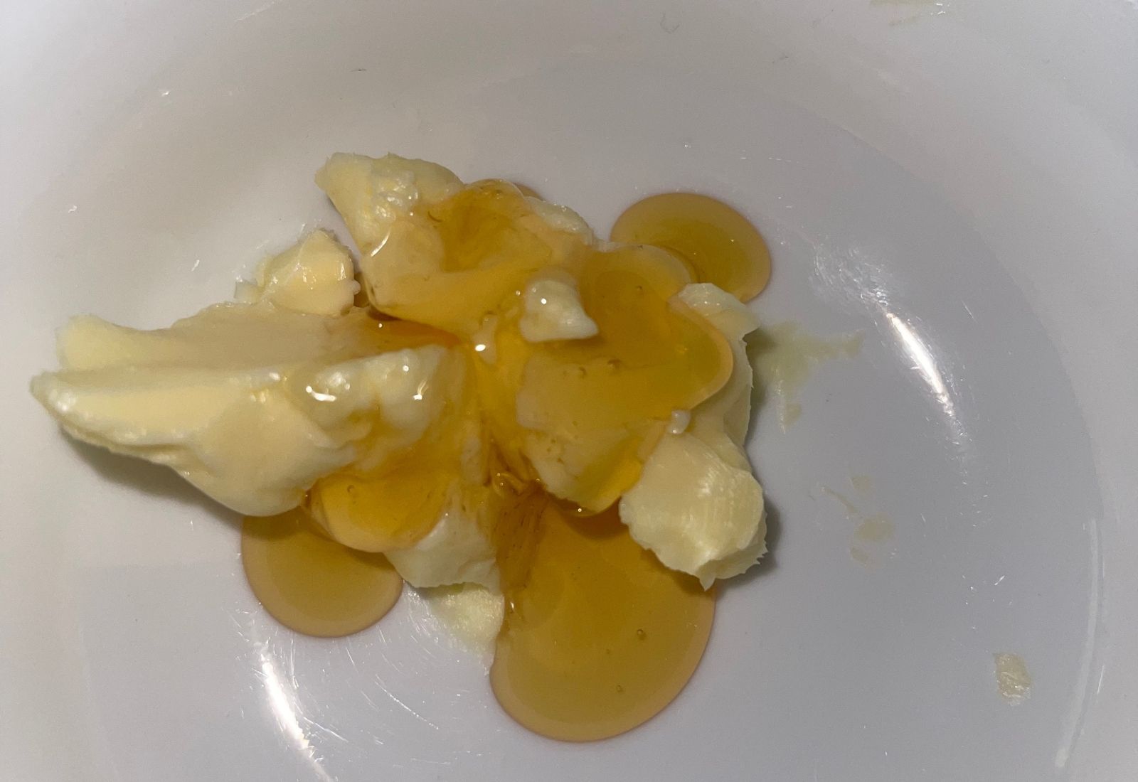 Bowl with softened butter and honey ready to be mixed into a warm glaze for cornbread or muffins.