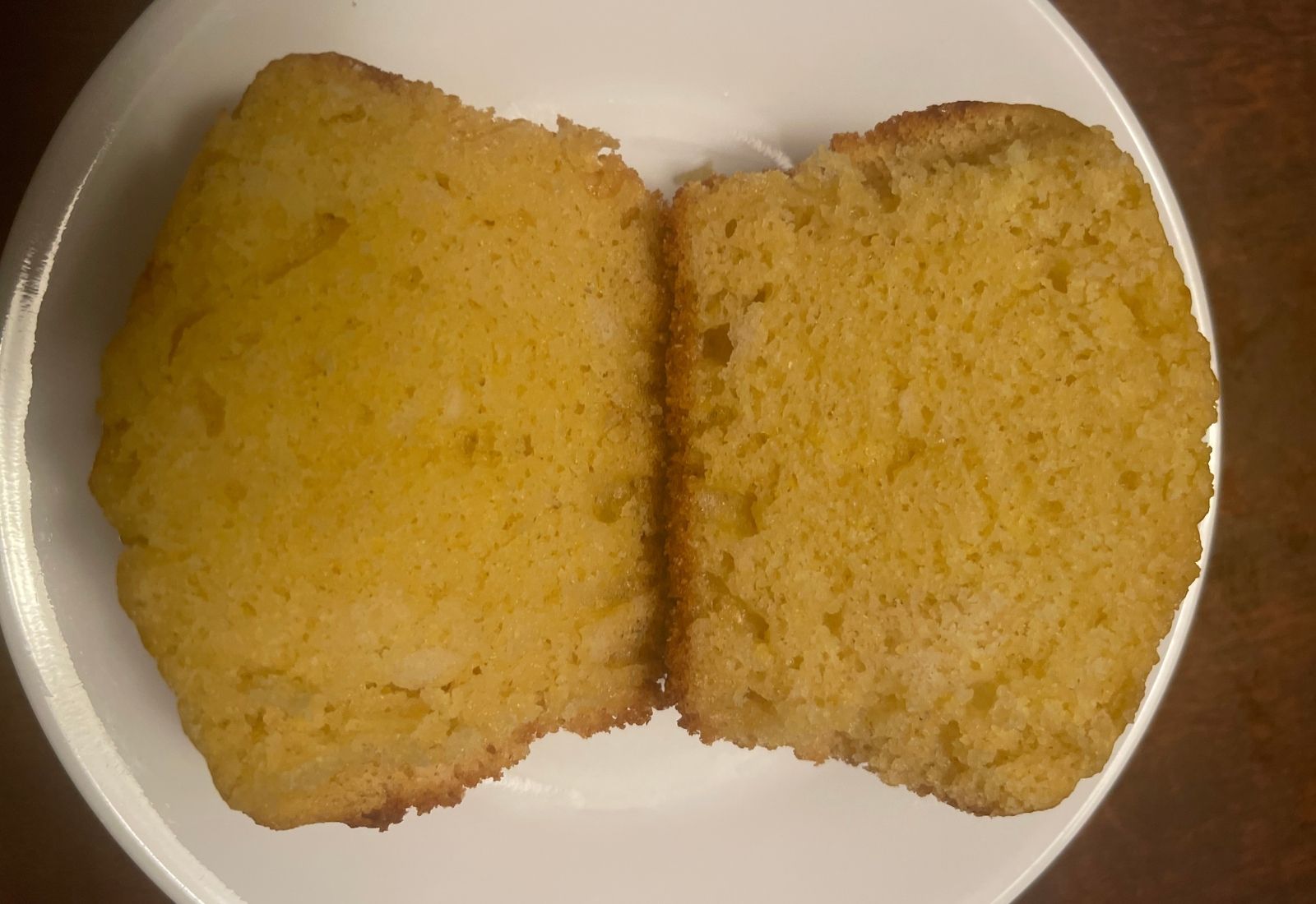 Honey sourdough corn muffin sliced open to show its soft, moist, tender crumb and golden color.