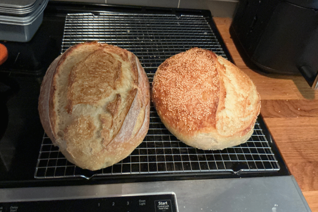 two golden sourdough loaves cooling on a wire rack after baking with balanced baker’s percentages