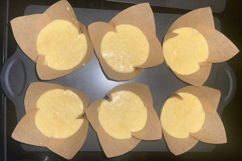 Unbaked sourdough honey cornbread batter portioned into tulip muffin liners before baking.
