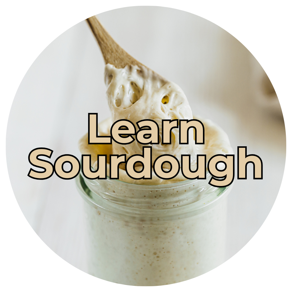 Learn Sourdough Glass jar of active sourdough starter being stirred, representing a learn sourdough category.