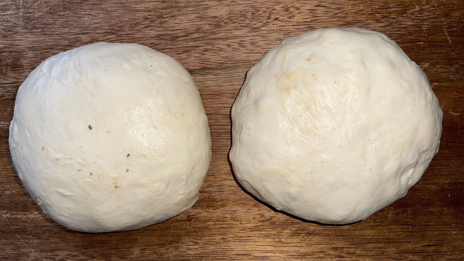 Pre-shaped champagne raisin sourdough dough resting on a wooden surface after bulk fermentation, showing smooth surface and gentle structure before final shaping.